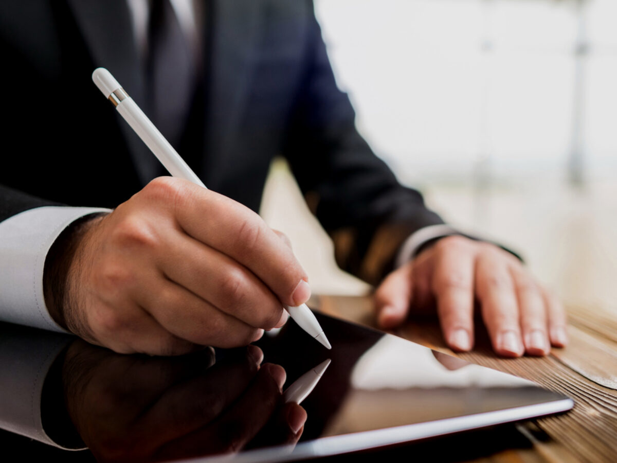 A close-up of a professional signing a settlement agreement digitally on a tablet, symbolising the legality of settlement agreements, relevant for Locate Solicitors.