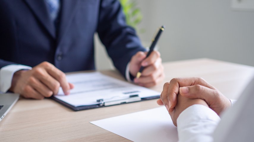 Two professionals sitting at a desk with documents and a clipboard, symbolising the process of proving workplace discrimination in the UK, relevant for Locate Solicitors.