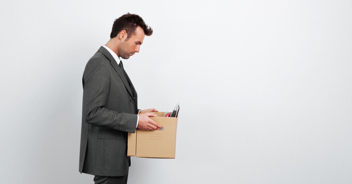 A professional man in a suit holding a box of personal belongings, symbolising unfair dismissal for gross misconduct in the UK, relevant for Locate Solicitors.