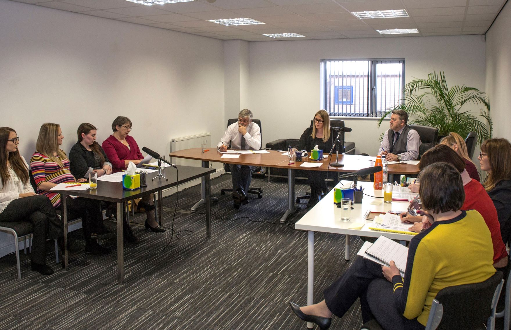 A tribunal panel discussing employment disputes in the UK, featuring solicitors and professionals in a formal meeting room setting.