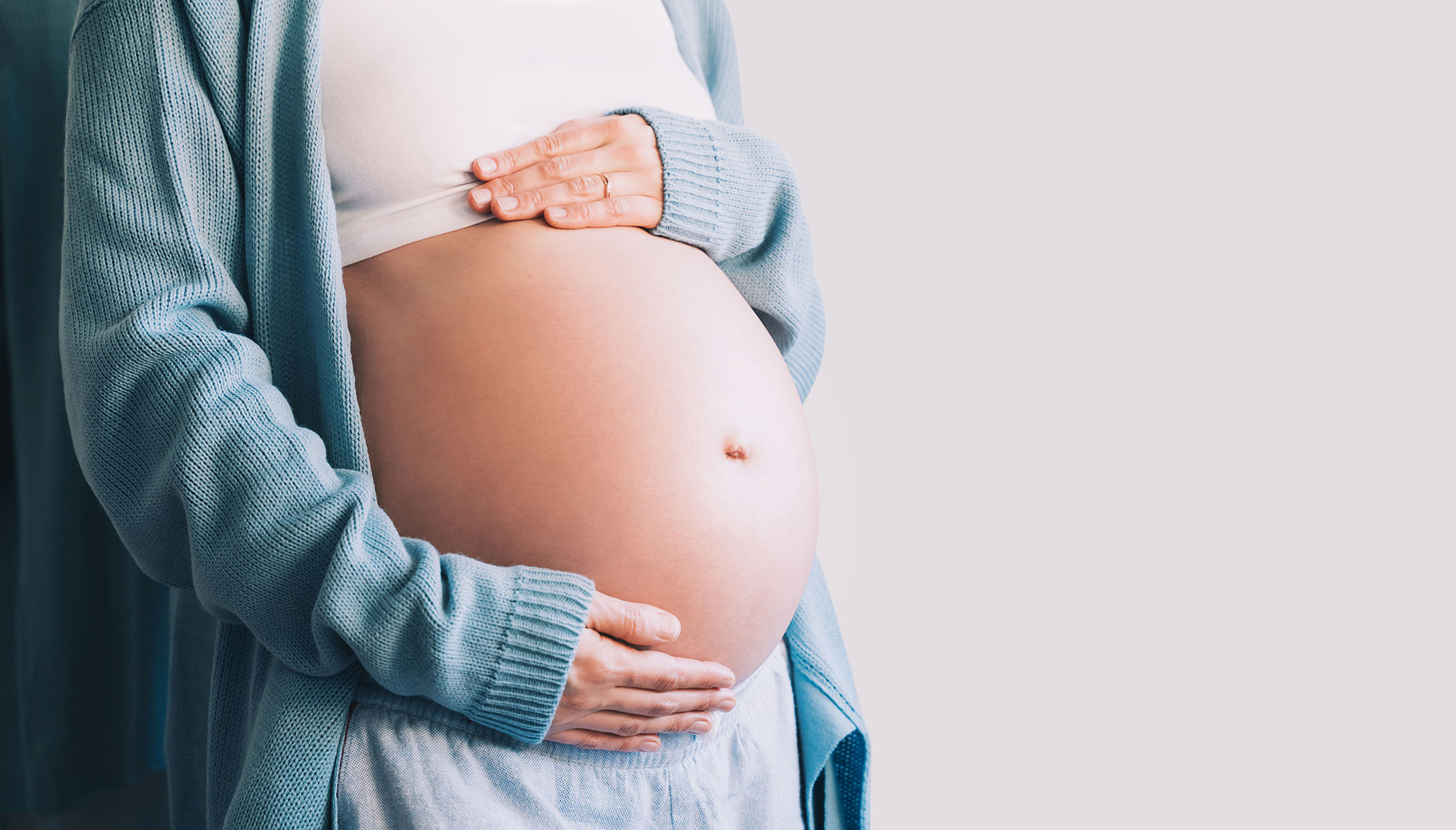 Close-up of a pregnant woman holding her belly, symbolising maternity leave and related legal entitlements.